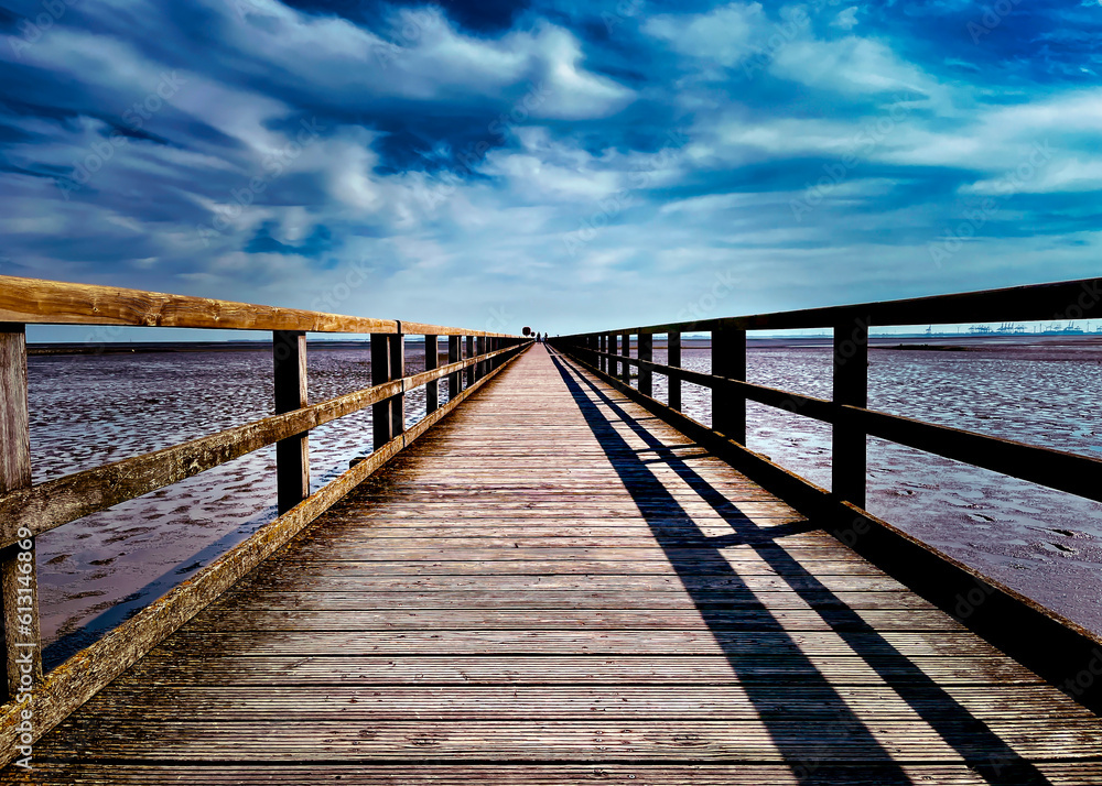 Endloser Weg: Am Burhavener Strand in Butjadingen erstreckt sich bei Ebbe ein faszinierender Steg in die Nordsee, der eine Illusion von unendlicher Schönheit schafft. Endloser Weg: Am Burhavener Strand in Butjadingen erstreckt sich bei Ebbe ein faszinierender Steg in die Nordsee, der eine Illusion von unendlicher Schönheit schafft.