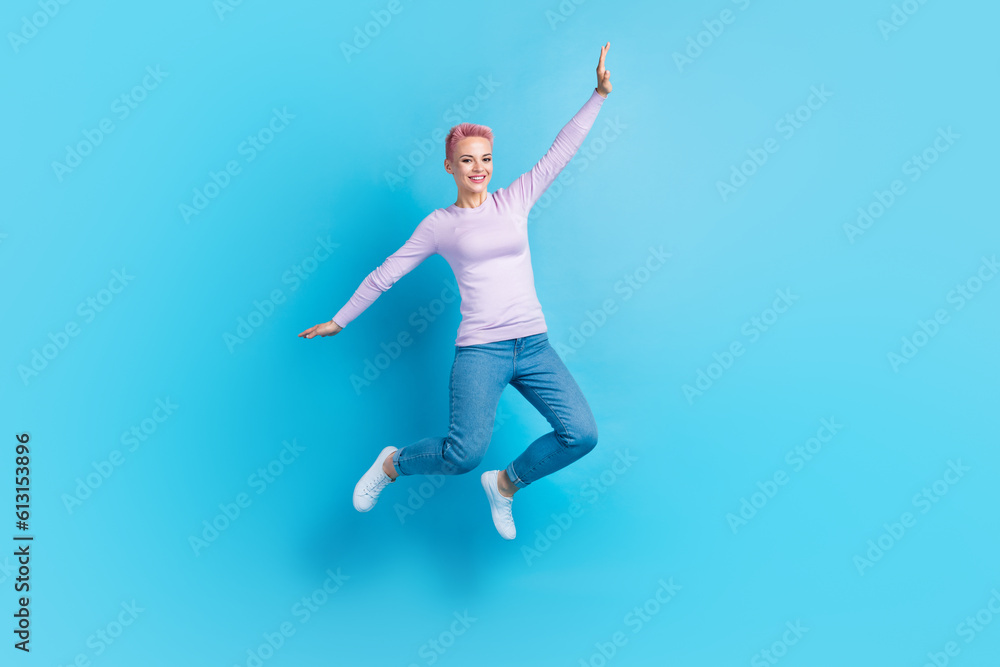 Full length body cadre of young girl jump fly arms wings careless have fun playing shopping deal advert isolated on blue color background Full length body cadre of young girl jump fly arms wings careless have fun playing shopping deal advert isolated on blue color background