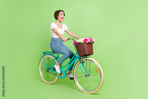 Full length photo of excited funky lady wear white top riding fast bicycle isolated green color background © deagreez