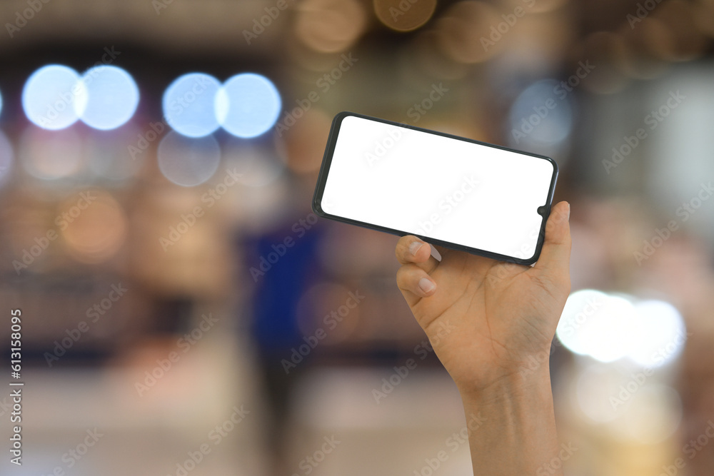 Hand holding smartphone with blank screen on bokeh light background Hand holding smartphone with blank screen on bokeh light background