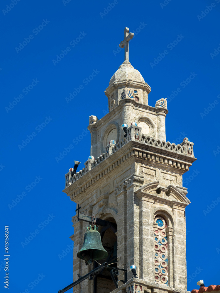 Church tower with bell against blue sky. Fanes, Rhodes island, Greece. Close up.