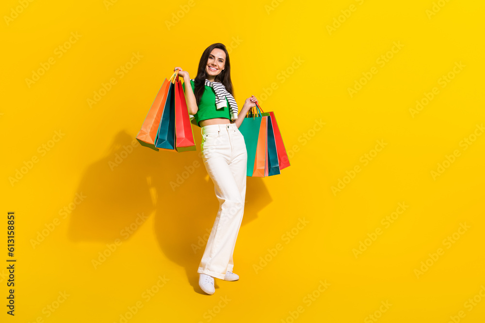Full size portrait of gorgeous cheerful girl hold boutique bags empty space clothes advert isolated on yellow color background Full size portrait of gorgeous cheerful girl hold boutique bags empty space clothes advert isolated on yellow color background
