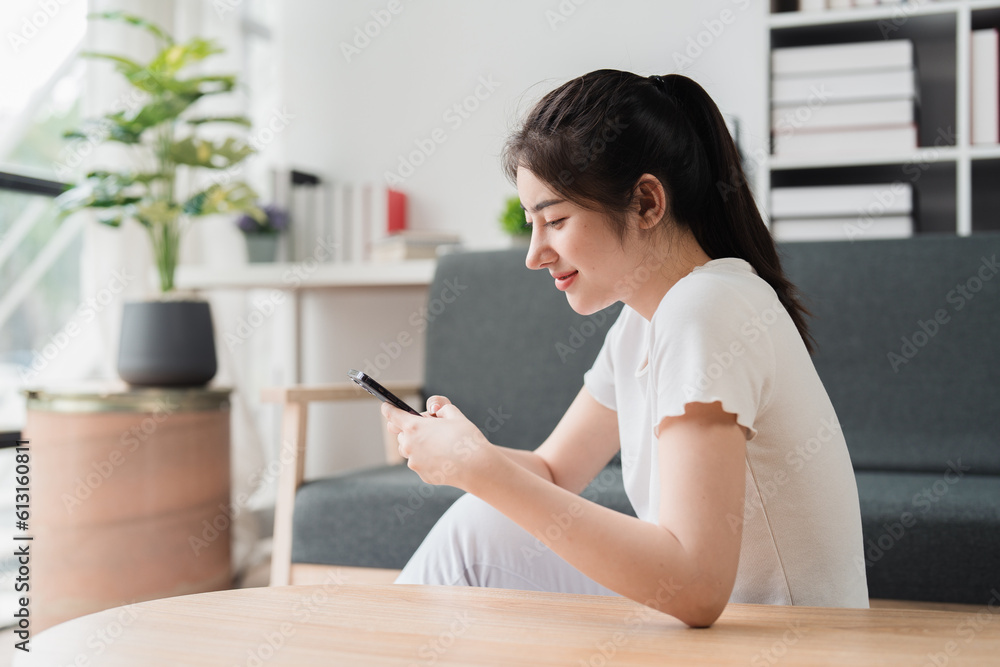 Young relaxed smiling pretty woman relaxing sitting on sofa at home. Female feeling joy enjoying with mobile phone on cozy couch Young relaxed smiling pretty woman relaxing sitting on sofa at home. Female feeling joy enjoying with mobile phone on cozy couch