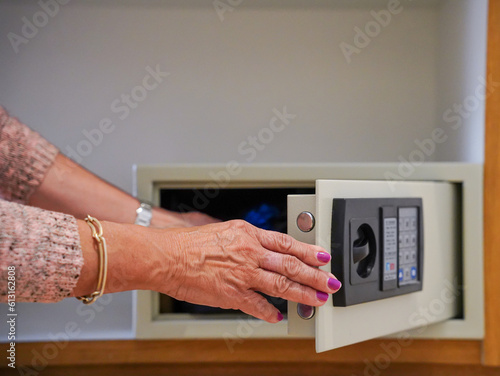 Unrecognizable woman opening the electronic safe in a hotel. Money and jewelry in the safe box