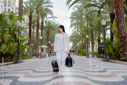 pretty tourist woman walks with suitcase on street in european city, europe tourism