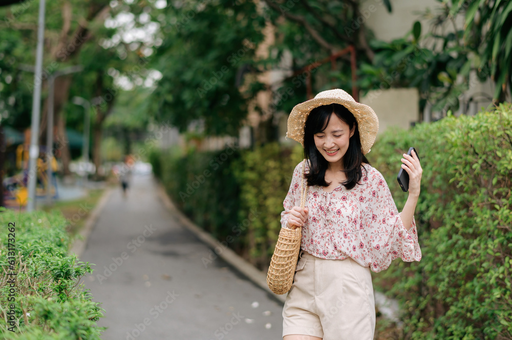 Portrait of asian young woman traveler with weaving hat and basket happy smile on green public park nature background. Journey trip lifestyle, world travel explorer or Asia summer tourism concept.