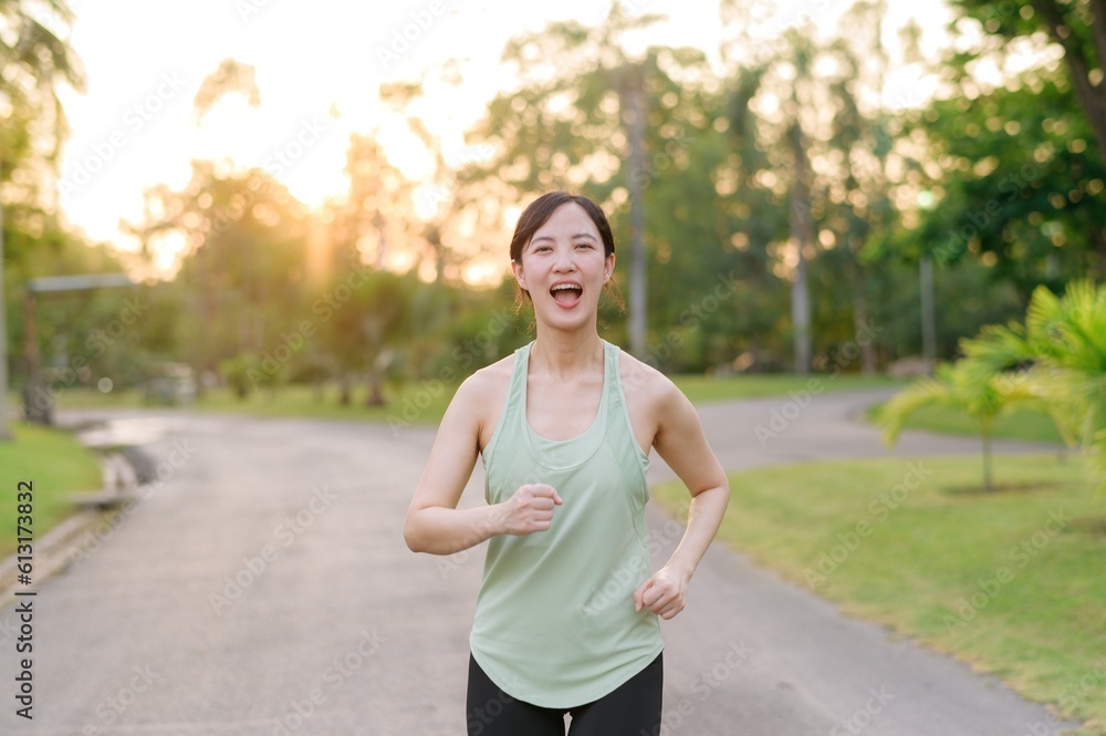 Fit Asian young woman jogging in park smiling happy running and enjoying a healthy outdoor lifestyle. Female jogger. Fitness runner girl in public park. healthy lifestyle and wellness being concept Fit Asian young woman jogging in park smiling happy running and enjoying a healthy outdoor lifestyle. Female jogger. Fitness runner girl in public park. healthy lifestyle and wellness being concept
