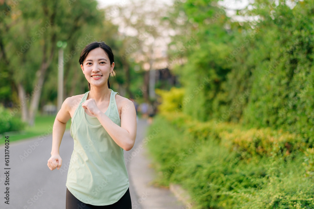 Fit Asian young woman jogging in park smiling happy running and enjoying a healthy outdoor lifestyle. Female jogger. Fitness runner girl in public park. healthy lifestyle and wellness being concept Fit Asian young woman jogging in park smiling happy running and enjoying a healthy outdoor lifestyle. Female jogger. Fitness runner girl in public park. healthy lifestyle and wellness being concept