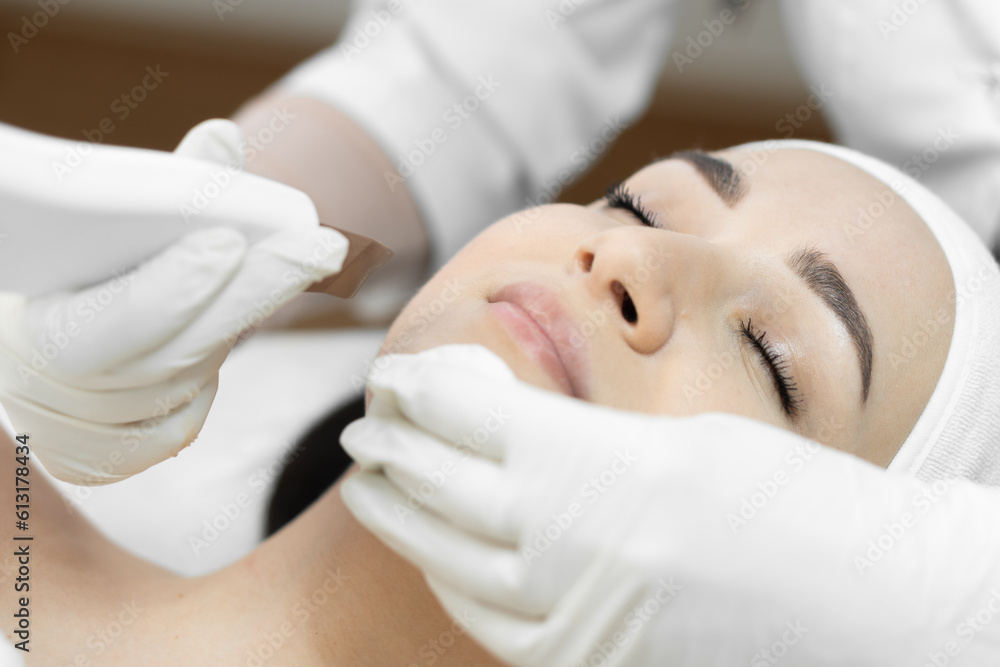 Naklejka premium The photo shows how ultrasonic facial cleansing from this professional cosmetologist helps to get rid impurities, excess seborrhea and sebum, creating healthy and fresh look of skin in beauty clinic