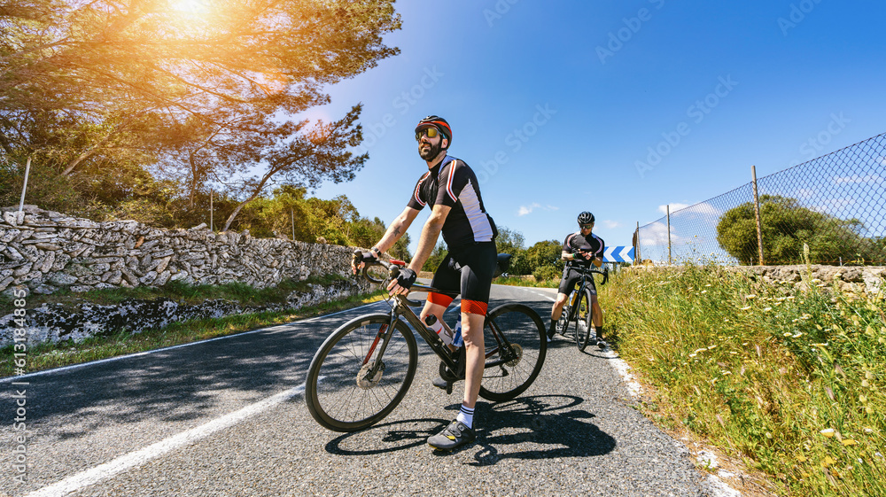 Obraz premium Mature Adult on a racing bike climbing the hill at mediterranean sea landscape coastal road
