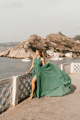 Woman sea green dress. Side view a happy woman with long hair in a long mint dress posing on a beach with calm sea bokeh lights on sunny day. Girl on the nature on blue sky background.