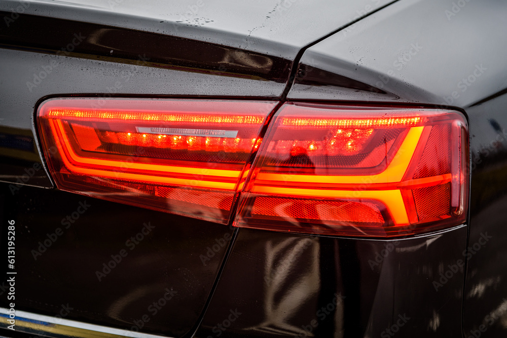 Right back modern headlight car. Car taillight. Detail black metallic car with rear light close up. Rear lamp signals for turning car on street. Signal function to keep them distance. Trunk closeup.