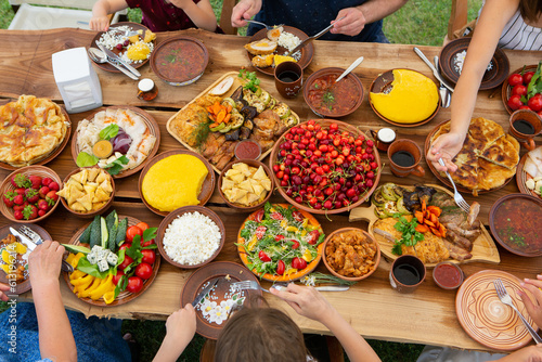 Homemade Romanian Food with grilled meat, polenta and vegetables Platter on camping. Romantic traditional moldavian food outside on the wood table. photo