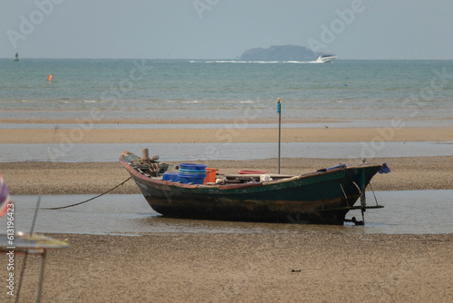 fisherman s fishing boat on sand at a fishing village beach There is an island and sea background with the daytime sky. stranded fishing boat After the sea has receded