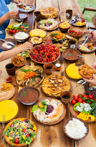 Homemade Romanian Food with grilled meat, polenta and vegetables Platter on camping. Romantic traditional moldavian food outside on the wood table.