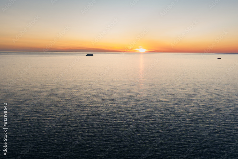 Obraz premium Sea sunset and the ferry sailing over the horizon.