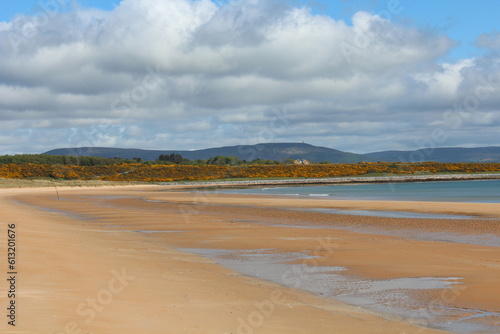 A beautiful view of the sandy coastline along the scottish coastline of Dornoch, in the highlands of Scotland. It is a sunny day with blue sky.