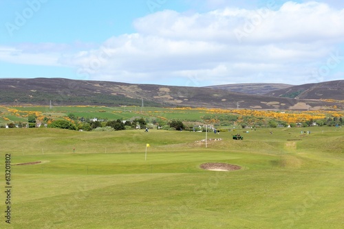 An incredible view of a golf hole in Scotland in the highlands of Scotland during spring with the gorse bush in full yellow bloom and beside the ocean, in Brora, Scotland photo