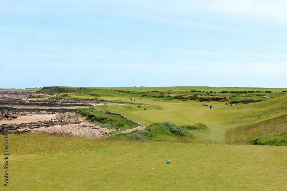 Naklejka premium An incredible view of a classic links golf hole with pot bunkers in Scotland with the ocean in nearby outside of St. Andrews, Scotland