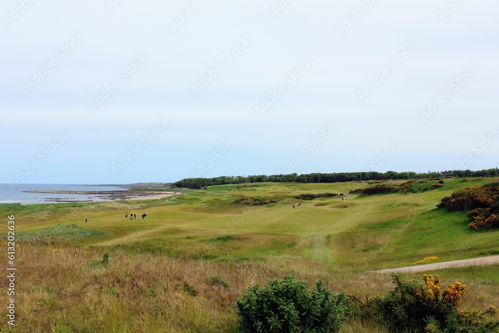 An incredible view of a classic links golf hole with pot bunkers in Scotland with the ocean in nearby outside of St. Andrews, Scotland
