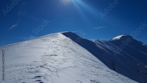 Raggio di sole sulla cima della montagna coperta di neve photo