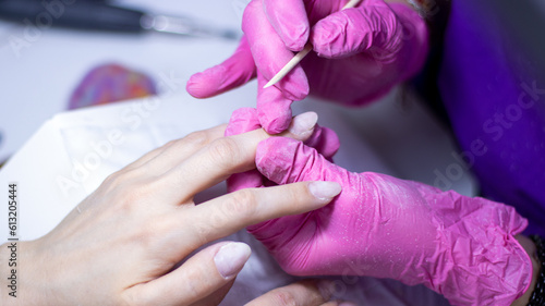 Cuticle removal. Services of professional manicurist in a beauty salon. Manicure and beauty sphere. Safety work in mask and rubber gloves.