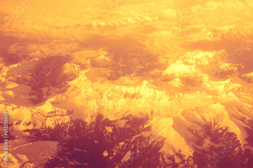 Aerial view of snowed mountains at sunrise our sunset. Majestic nature earth landscapes. Abstract retro art background.