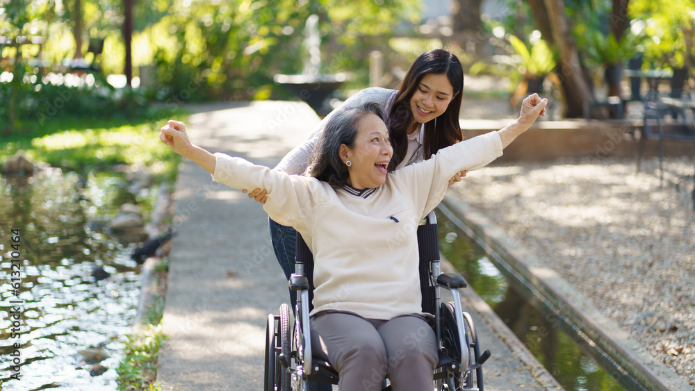 Obraz premium Asian senior woman in wheelchair with happy daughter. Family relationship retired woman sitting on wheelchair in the park age care at retirement home.