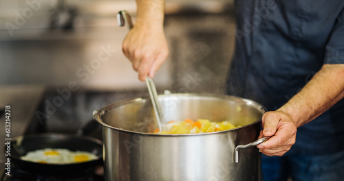 Wallpaper Mural Panorama, Koch rührt Eintopf in einem großen Topf. Die Schärfe liegt nur auf einer Hand. Torontodigital.ca