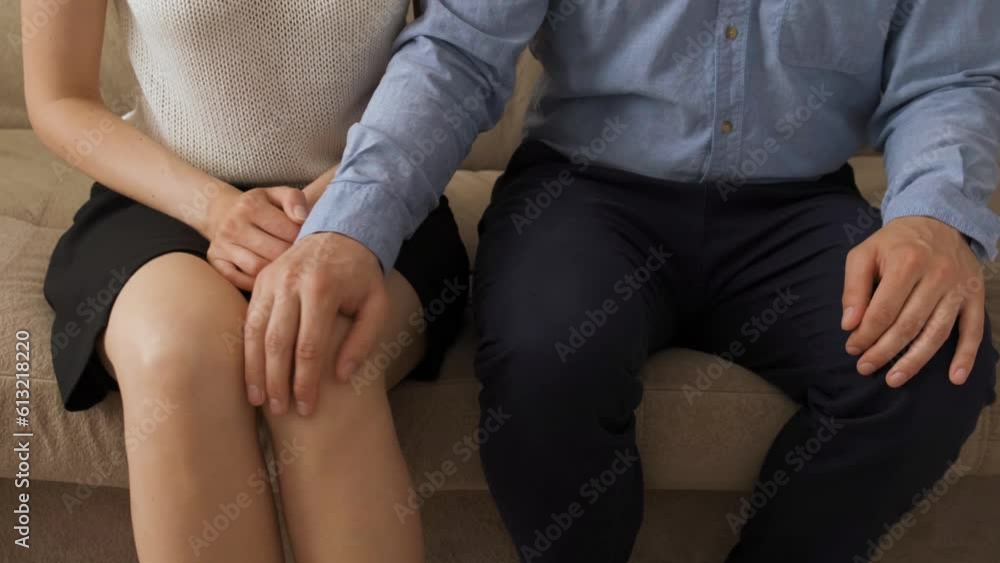 A man and a woman are sitting on the sofa in the living room during the day. He puts his hand on her knee and squeezes it, trying to molest. The woman breaks out A man and a woman are sitting on the sofa in the living room during the day. He puts his hand on her knee and squeezes it, trying to molest. The woman breaks out