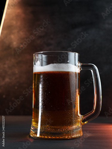 cold beer mug in drops of water on a dark table,