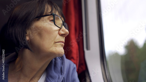 Elderly lady in glasses travels in train and looking out the window © Andriy Nekrasov