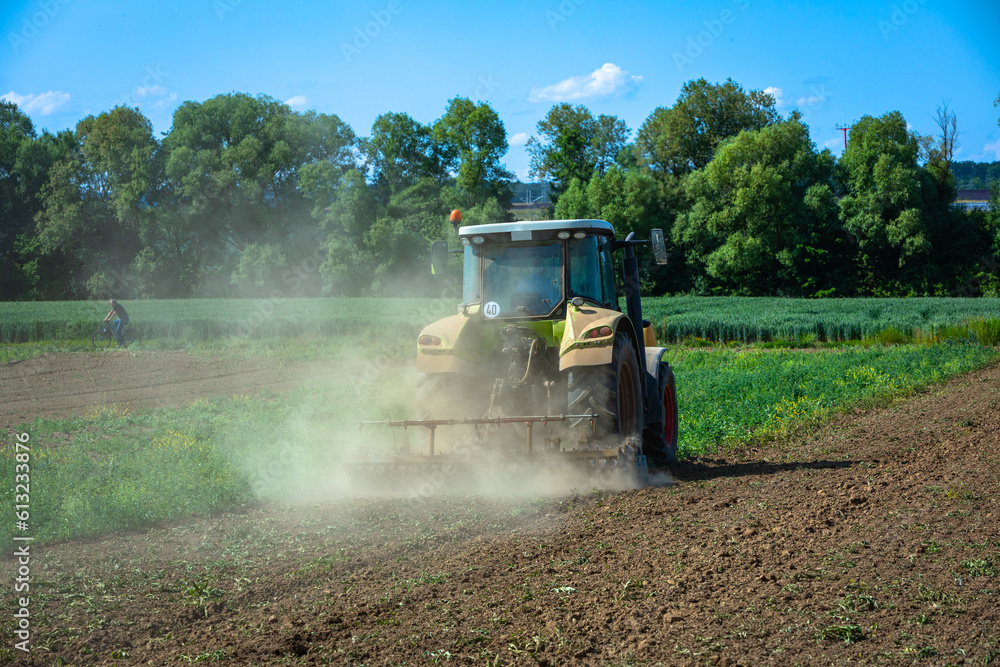 Fototapeta premium dust rising up as tractor grinds field