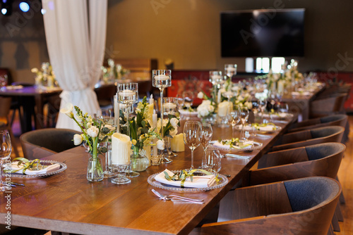 A general plan of a festive tables decorated with a white trees  chairs  plates  compositions of white flowers and candles. Wedding decoration and decor