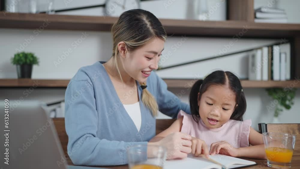 Young asian mother teaching daughter to do homework. Excited and overjoyed young Asian mother and daughter raising hands for sucess. Education concept Young asian mother teaching daughter to do homework. Excited and overjoyed young Asian mother and daughter raising hands for sucess. Education concept