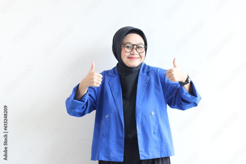 beautiful young Asian Muslim woman, wearing glasses and blue blazer with hand gesture of approval or OK beautiful young Asian Muslim woman, wearing glasses and blue blazer with hand gesture of approval or OK