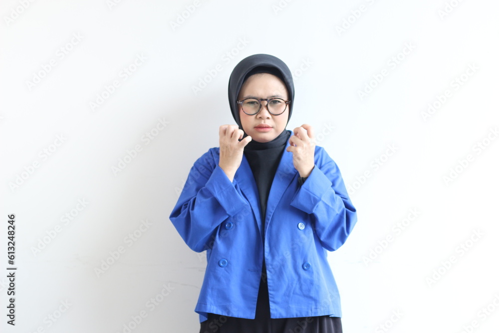 Young beautiful Asian Muslim woman, wearing glasses and blue blazer with angry facial expression Young beautiful Asian Muslim woman, wearing glasses and blue blazer with angry facial expression
