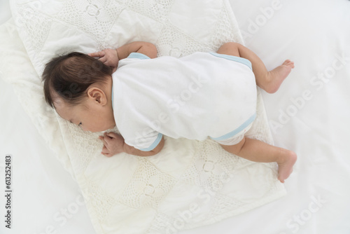 Photography Top view of newborn baby sleeping on blanket on white bed