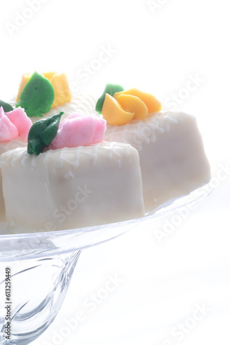 White petit fours on a white background with pink and yellow flowers