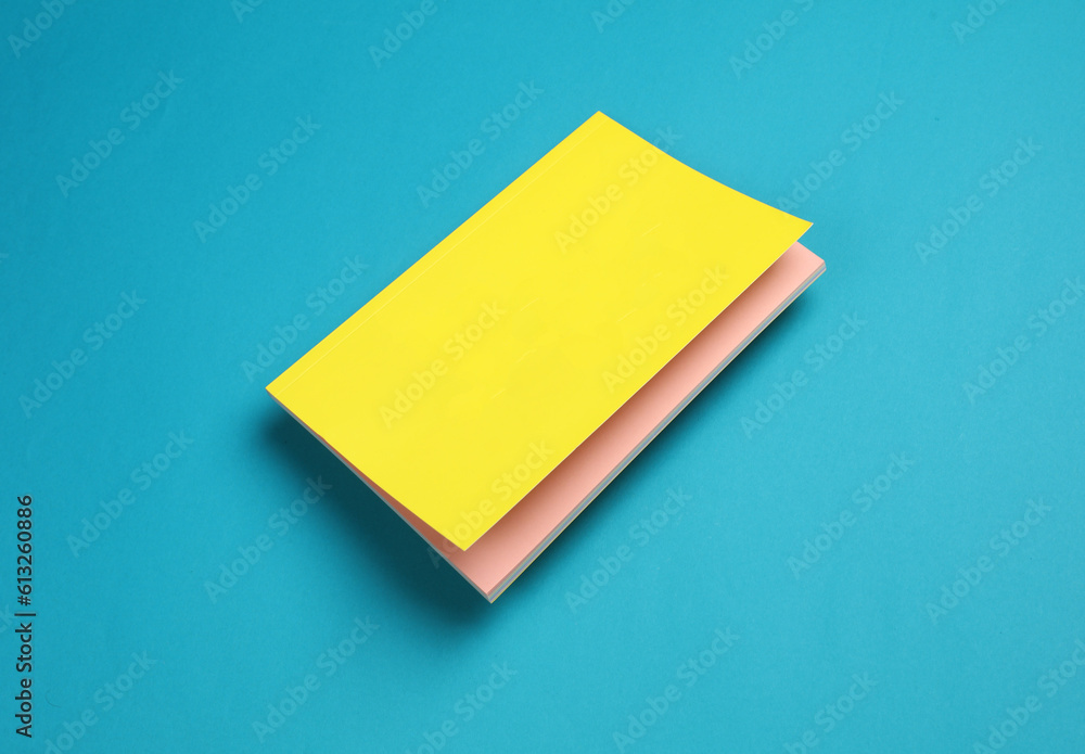 Notepad with a yellow cover floating on blue background Notepad with a yellow cover floating on blue background