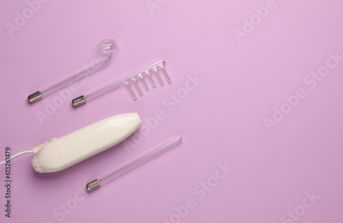 Acne treatment. Device for local darsonvalization with nozzles on a purple background. Beauty concept. Flat lay. Copy space