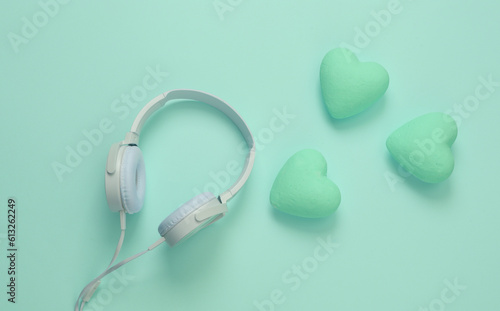 Headphones with hearts on blue background. Romantic melody. Top view