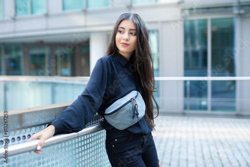 trend fashion teenage girl look to side and pose with her grey noname fanny pack at shoulder while being confident with this statement casual fashion piece