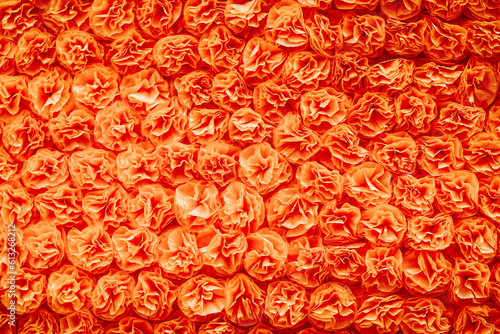 Fleurs en papier crépon orange fait main pour décorer un char dans une fête - Arrière plan coloré