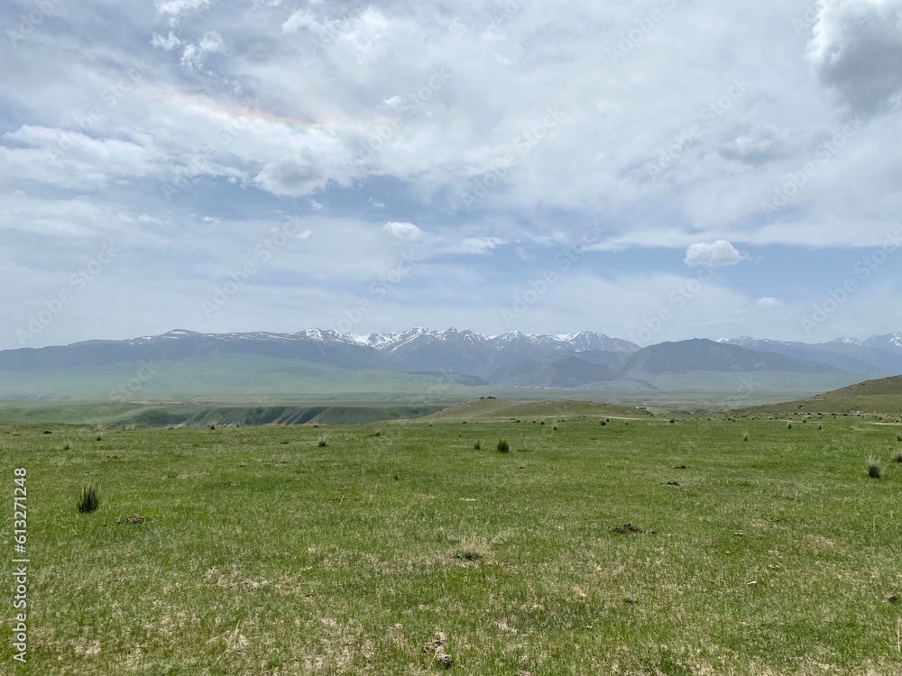 Morning in the mountains. Green meadow, mountains, blue sky with clouds. Beautiful landscape of Kazakhstan Morning in the mountains. Green meadow, mountains, blue sky with clouds. Beautiful landscape of Kazakhstan