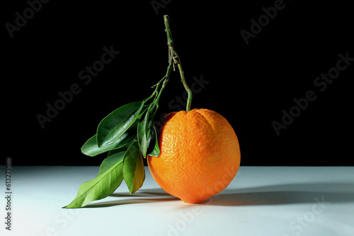 Slika na platnu still life, close up of an orange with leaves on white table and black backgroun