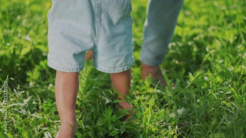 baby first step. happy family baby kid concept. baby bare feet makes the first steps on the green grass in the park. baby learns to walk on the grass with dream bare feet in the park in summer world baby first step. happy family baby kid concept. baby bare feet makes the first steps on the green grass in the park. baby learns to walk on the grass with dream bare feet in the park in summer world