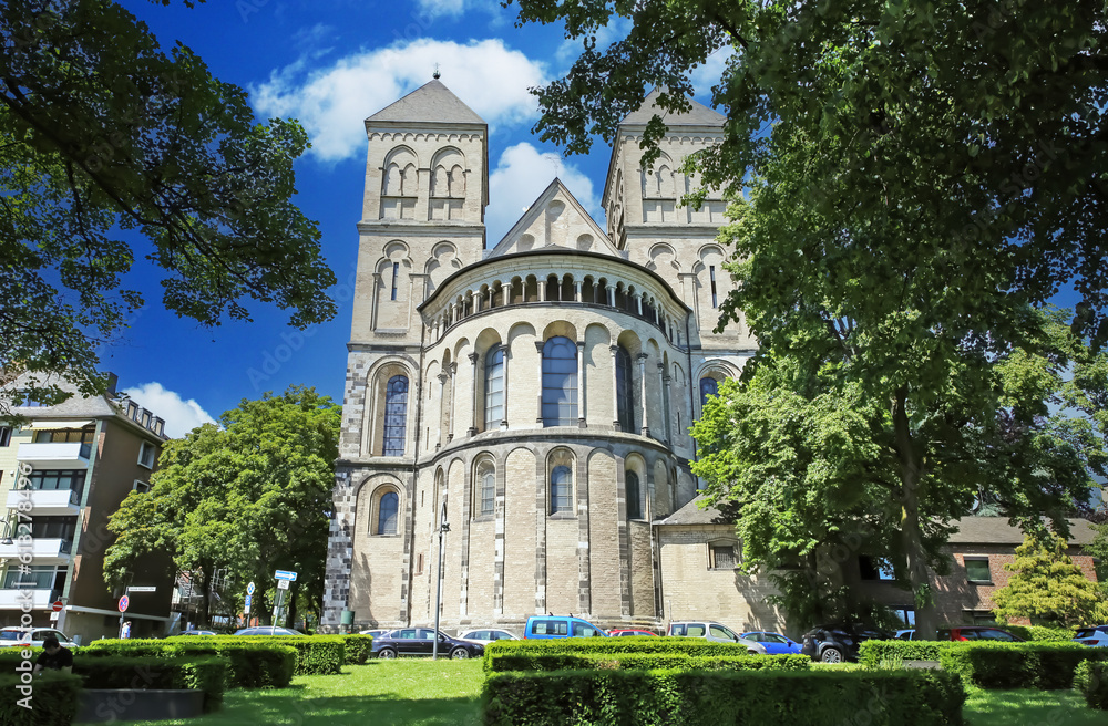 Cologne (Köln), Germany - June 6. 2023: Beautiful romanesque architecture medieval german St. Kunibert church from 12th century with green trees park in summer Cologne (Köln), Germany - June 6. 2023: Beautiful romanesque architecture medieval german St. Kunibert church from 12th century with green trees park in summer