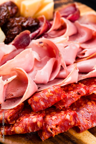 Various types of meat slices of sausage, ham, cheese, sun-dried tomatoes and bread.