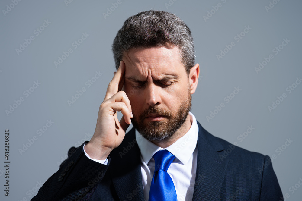 Tired man having a terrible headache. Exhausted man feeling unhealthy, upset about headache illness. Stressed middle-aged man with headache isolated on gray. Migraine and headache concept. Tired man having a terrible headache. Exhausted man feeling unhealthy, upset about headache illness. Stressed middle-aged man with headache isolated on gray. Migraine and headache concept.